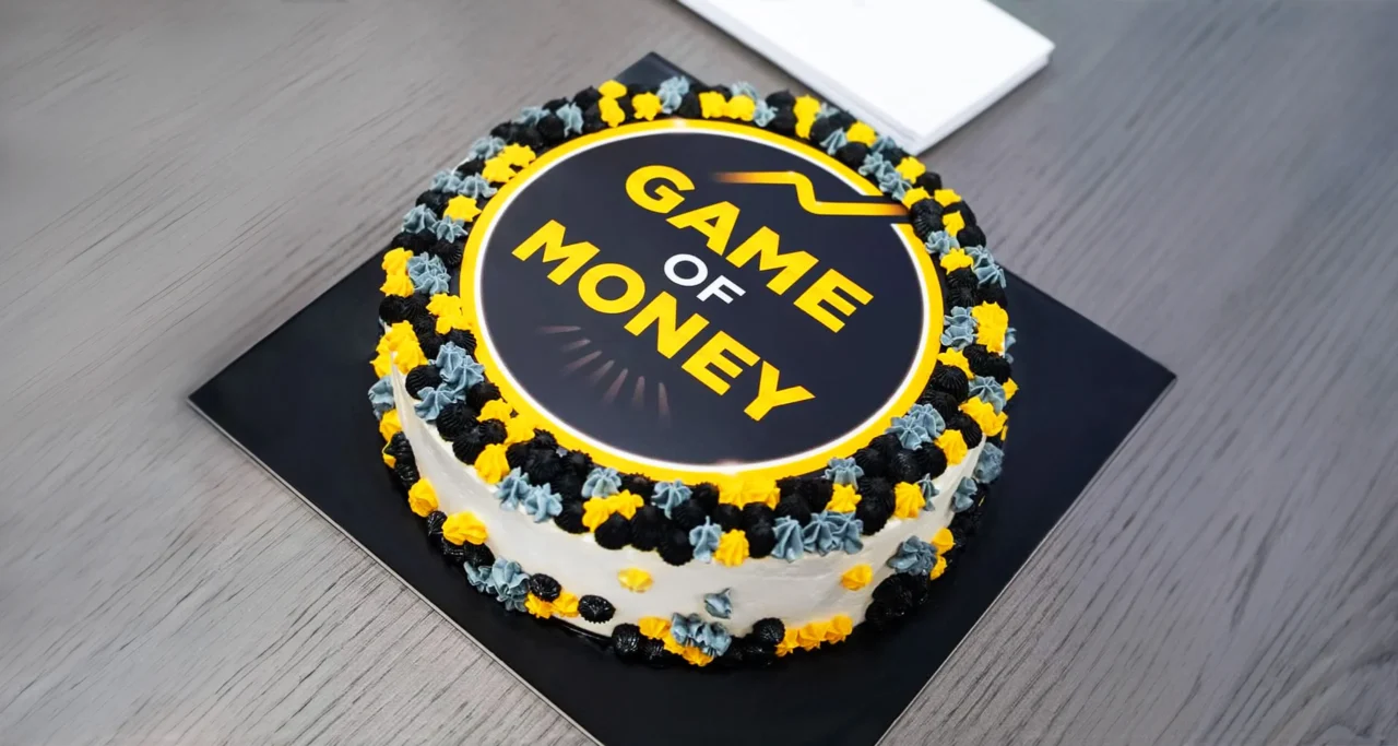 Game of Money branded celebration cake featuring the logo
